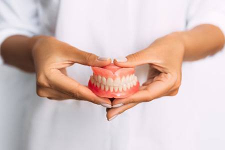 Lady presents viewer with dentures