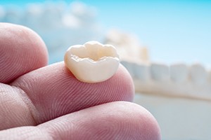 A dental crown on a fingertip