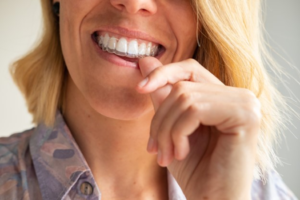 a patient smiling and holding their retainer